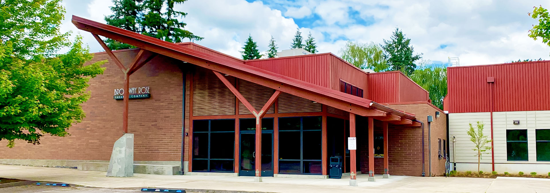 Photo of the front of the New Stage Theatre from the parking lot on a bright, sunny spring day.