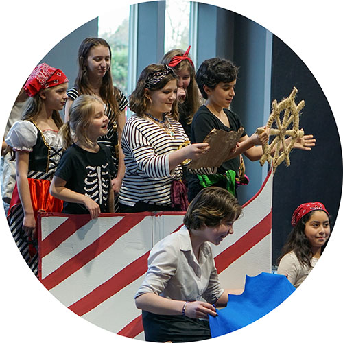 Photo from one of our Kids Showcases, showing a scene of the kids singing in a makeshift pirate ship.