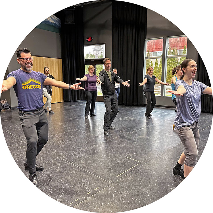 Photo from one of our tap classes, the students all posing with their arms out in front of them, all dancing together as one.