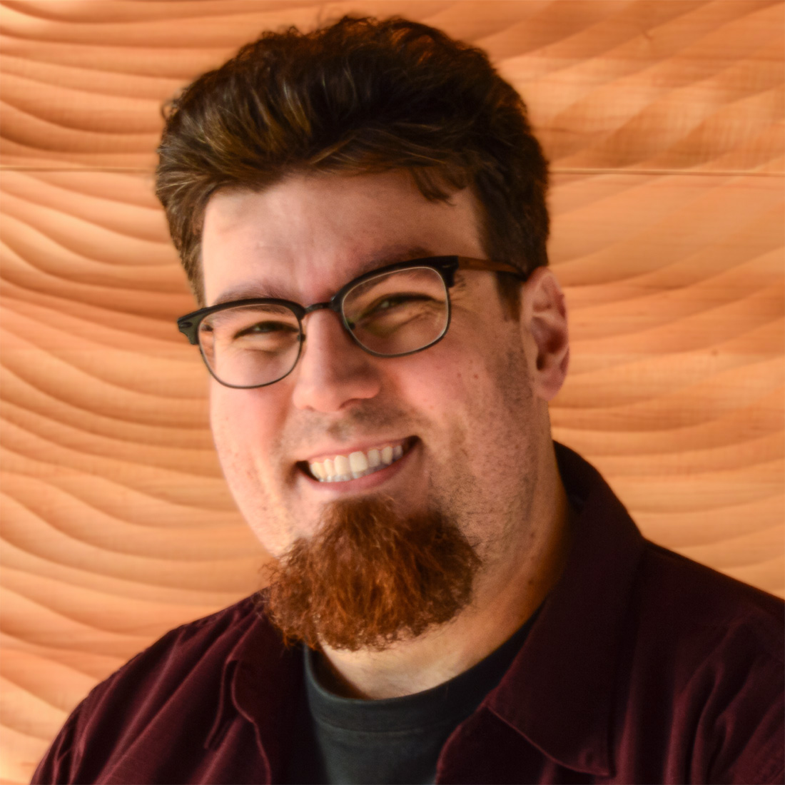 Photo of Brian Moen in front of the carved wood wall in the Broadway Rose lobby.