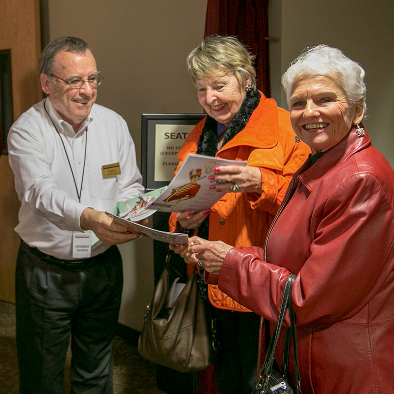 A photo of Broadway Rose volunteers and patrons greeting each other at the theatre house entrance, smiling and ready to see a show.