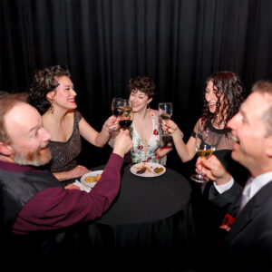 Photo of a table of guests at our 2024 Gala, all enjoying a cheers with their glasses, smiling and laughing together.